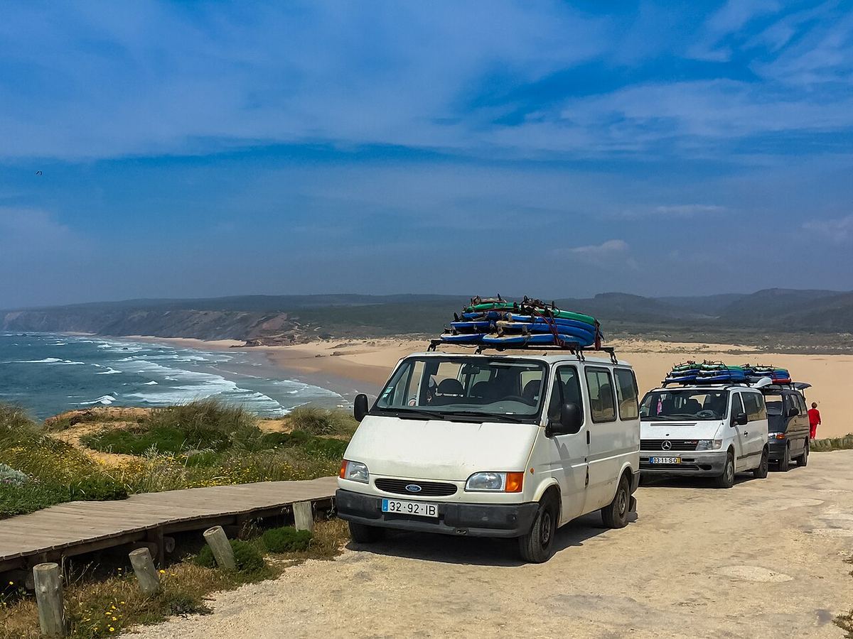Busse einer Surfschule mit Boards auf dem Dach an der Algarve (Portugal).